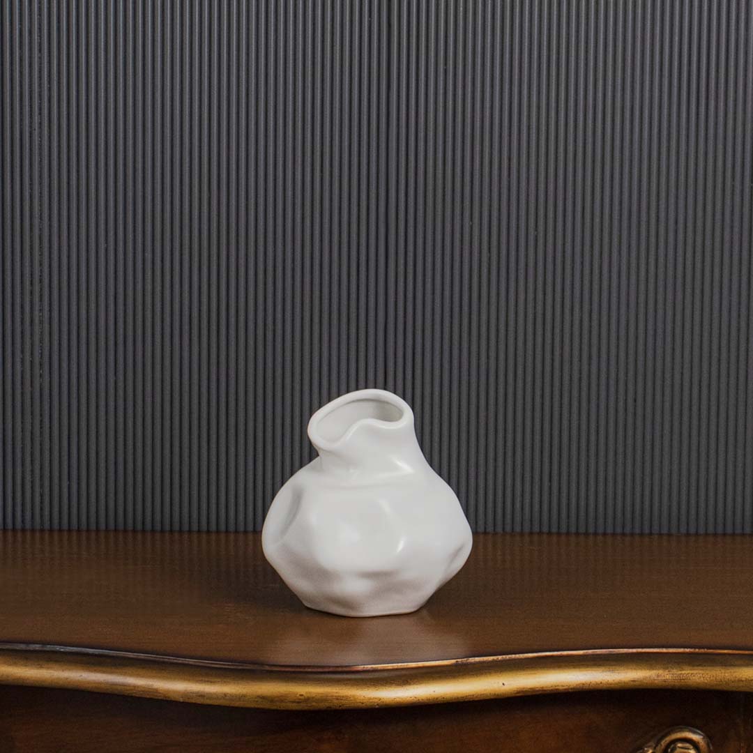 Contemporary white ceramic vase with sculptural design shown on black background highlighting its elegant silhouette.