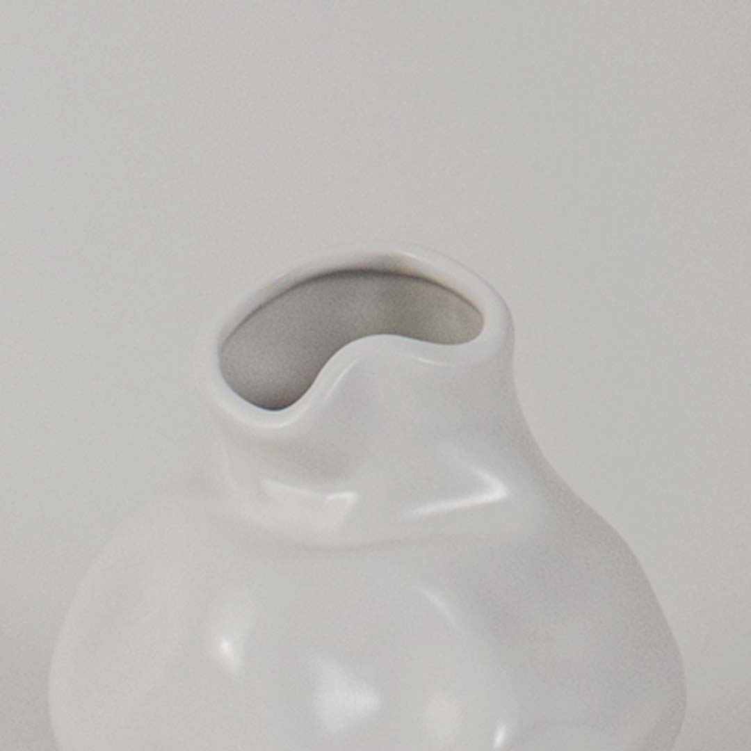 Closeup of white ceramic vase showing smooth glossy texture and curved shape ideal for minimalist decor aesthetics.