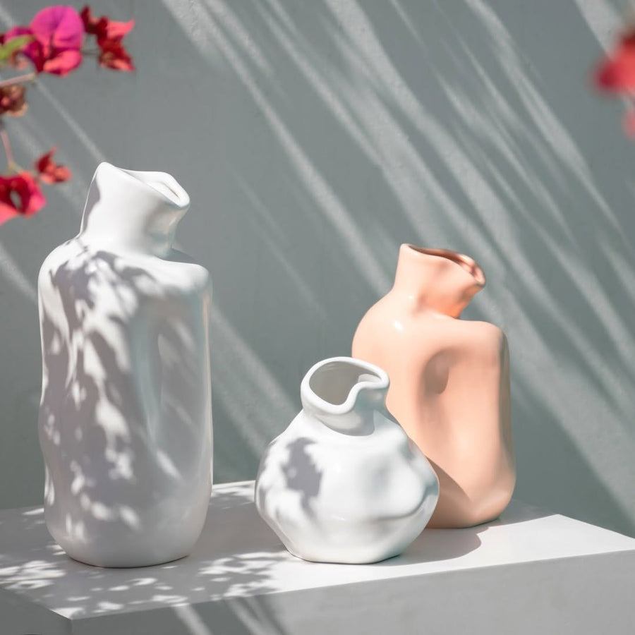 Sculptural white ceramic vase styled beside books and dried flowers adds modern artistic touch to home interiors.