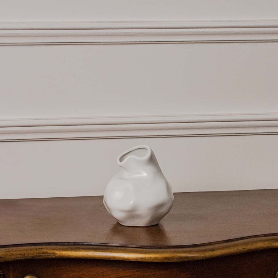 White ceramic vase with wavy neck and glossy finish displayed on white background perfect for floral arrangements.