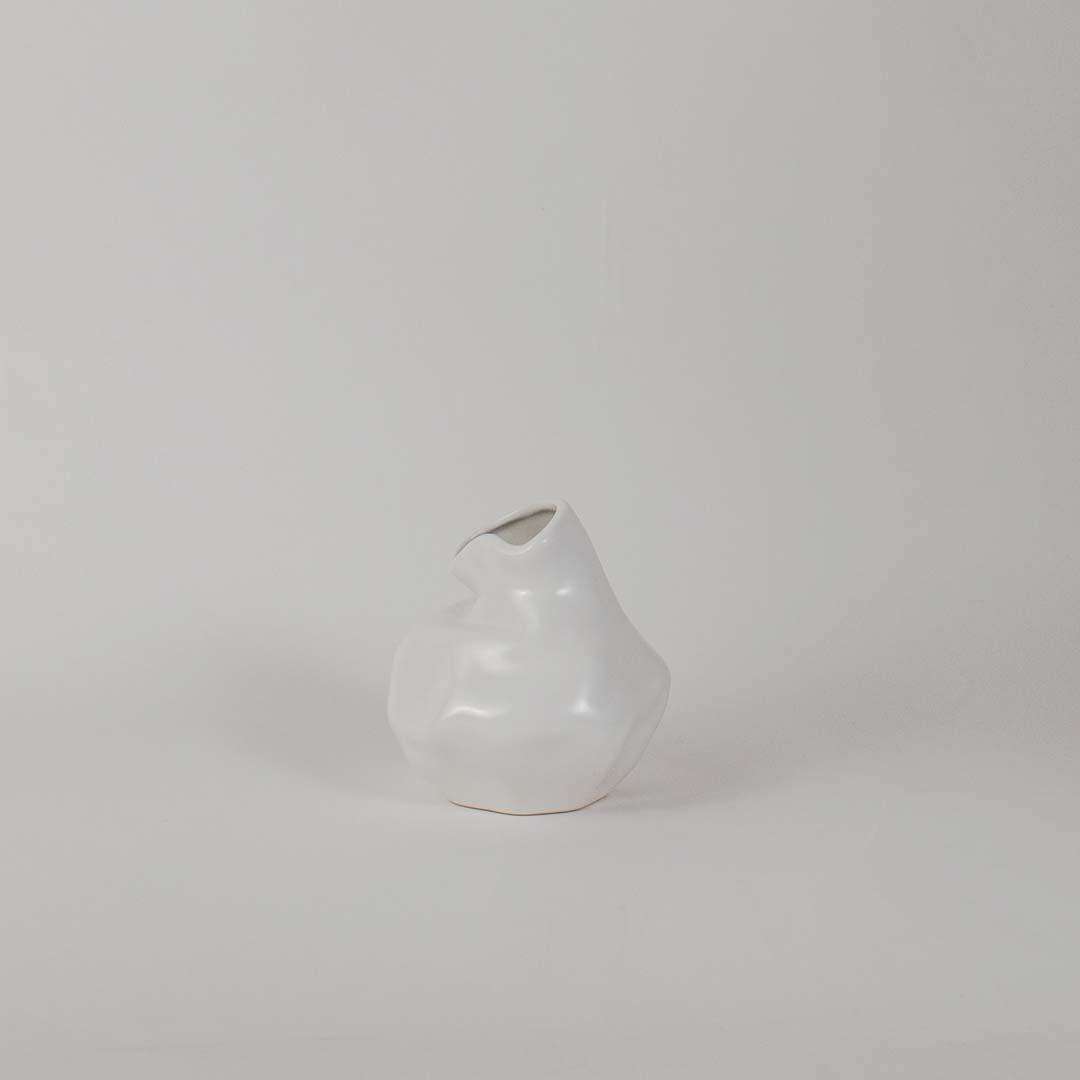 Modern glossy white ceramic vase with artistic uneven shape displayed on white background for interior decoration.