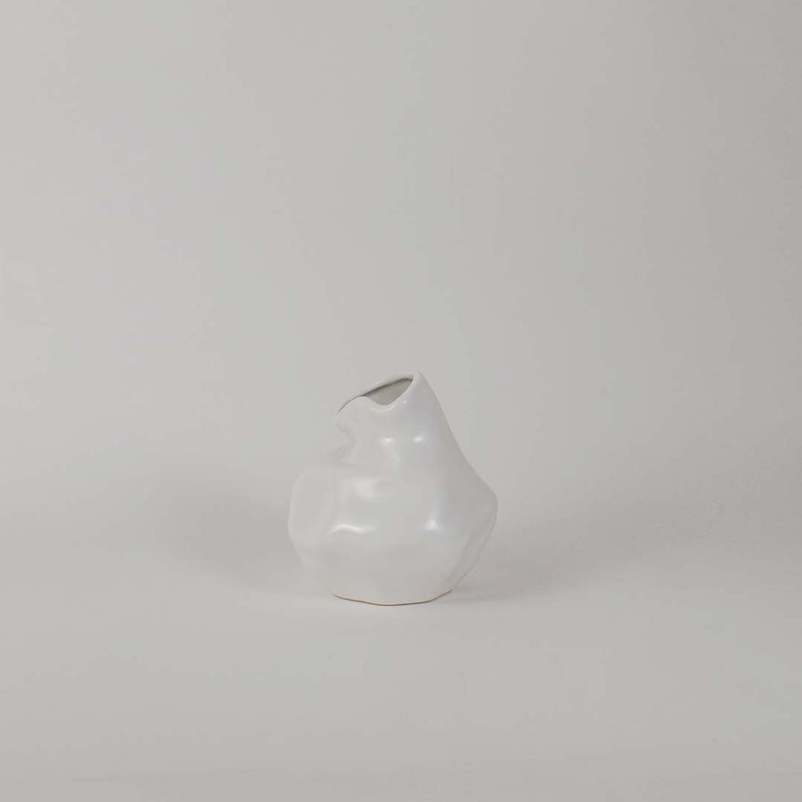 Modern glossy white ceramic vase with artistic uneven shape displayed on white background for interior decoration.