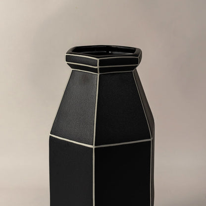 Closeup of black ceramic vase with textured matte finish and white outlined grid design highlighting contemporary craftsmanship.