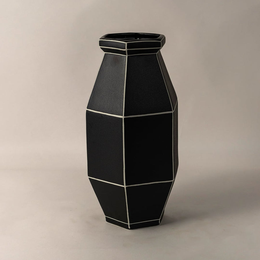 Side angle view of black ceramic vase with contemporary geometric shape and white line accents designed for elegant interiors.
