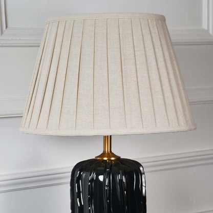 White pleated fabric shade with gold stem detail on black ceramic table lamp showcasing luxury craftsmanship and style.