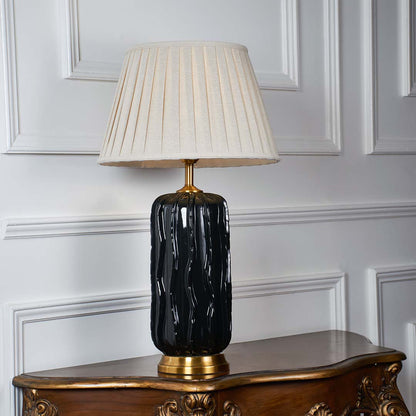 White pleated shade table lamp with glossy black ceramic base and gold accent for elegant bedroom and living room decor.