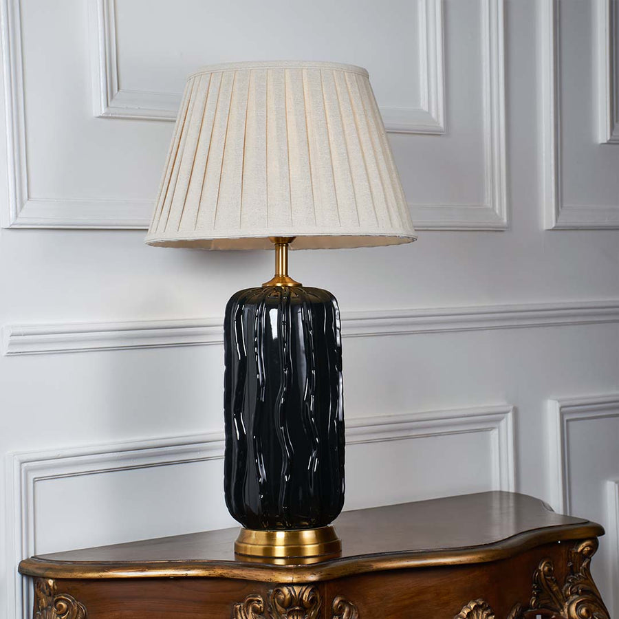 White pleated shade table lamp with glossy black ceramic base and gold accent for elegant bedroom and living room decor.