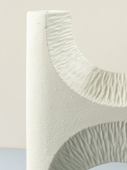 Closeup of white ceramic vase highlighting detailed textured finish and modern arch cutout design for decor styling.