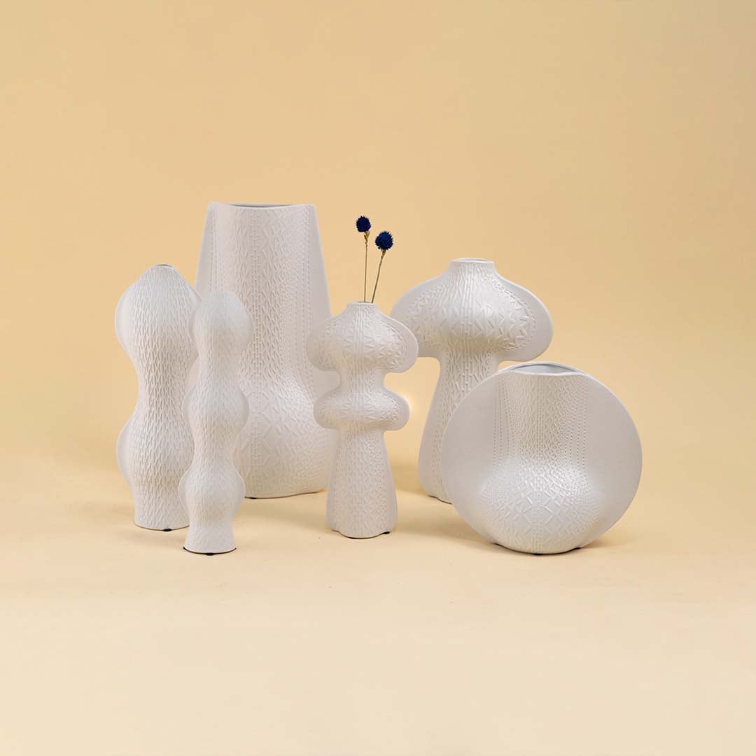 Set of modern white textured vases in unique artistic shapes arranged together for a refined contemporary decor look.