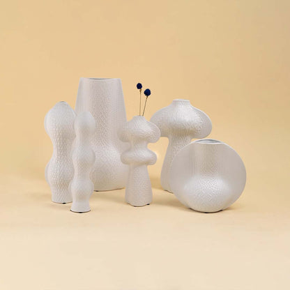Set of modern white textured vases in unique artistic shapes arranged together for a refined contemporary decor look.