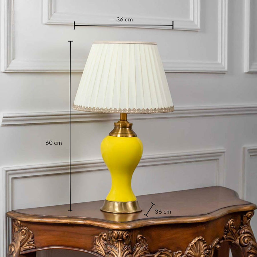 Yellow ceramic table lamp with pleated fabric shade and golden base shown with 60cm height and 36cm width.