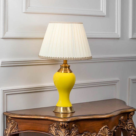 Table lamp with bright yellow ceramic base and white fabric shade on wooden console table classic lighting for living room decor.