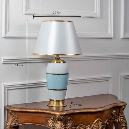 Elegant table lamp with white and blue ceramic base and white shade on wooden side table classic lighting for bedroom decor.

