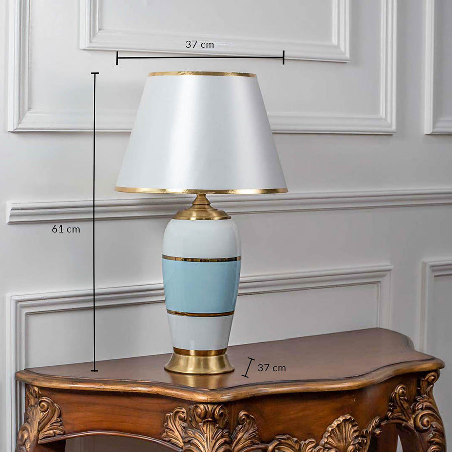 Elegant table lamp with white and blue ceramic base and white shade on wooden side table classic lighting for bedroom decor.
