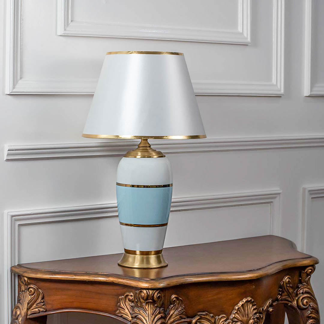 Decorative table lamp with white shade and blue ceramic base on wooden table ideal for bedroom and living room decor lighting.
