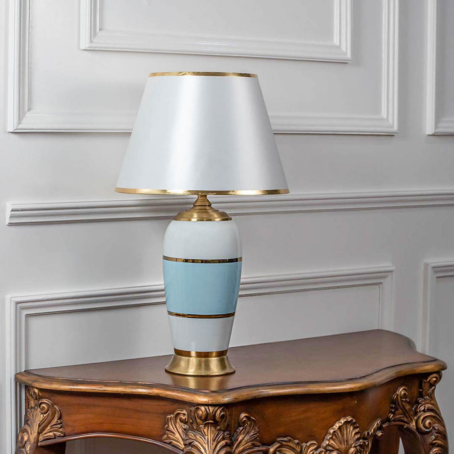 Decorative table lamp with white shade and blue ceramic base on wooden table ideal for bedroom and living room decor lighting.