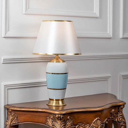 Table lamp with white and blue ceramic base and white fabric shade on wooden console table classic elegant lighting for living room decor.