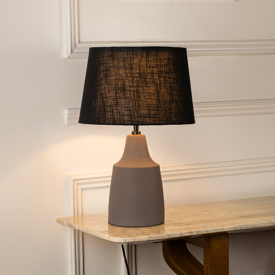 Table lamp with dark fabric shade and ceramic base perfect for elegant bedroom or living room table decor styling on clean background.