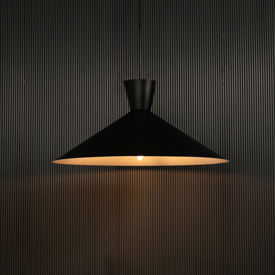 Black cone pendant light against dark panel wall with light on for stylish contemporary décor.