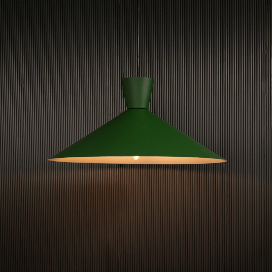 Green cone pendant light hanging against dark textured wall with light on for earthy modern décor.