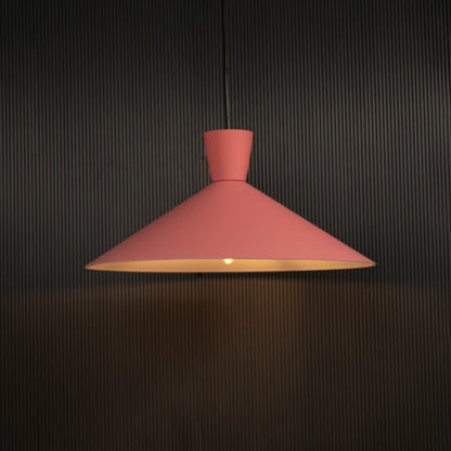 Pink cone pendant light hanging against dark textured wall with light on for playful modern décor.