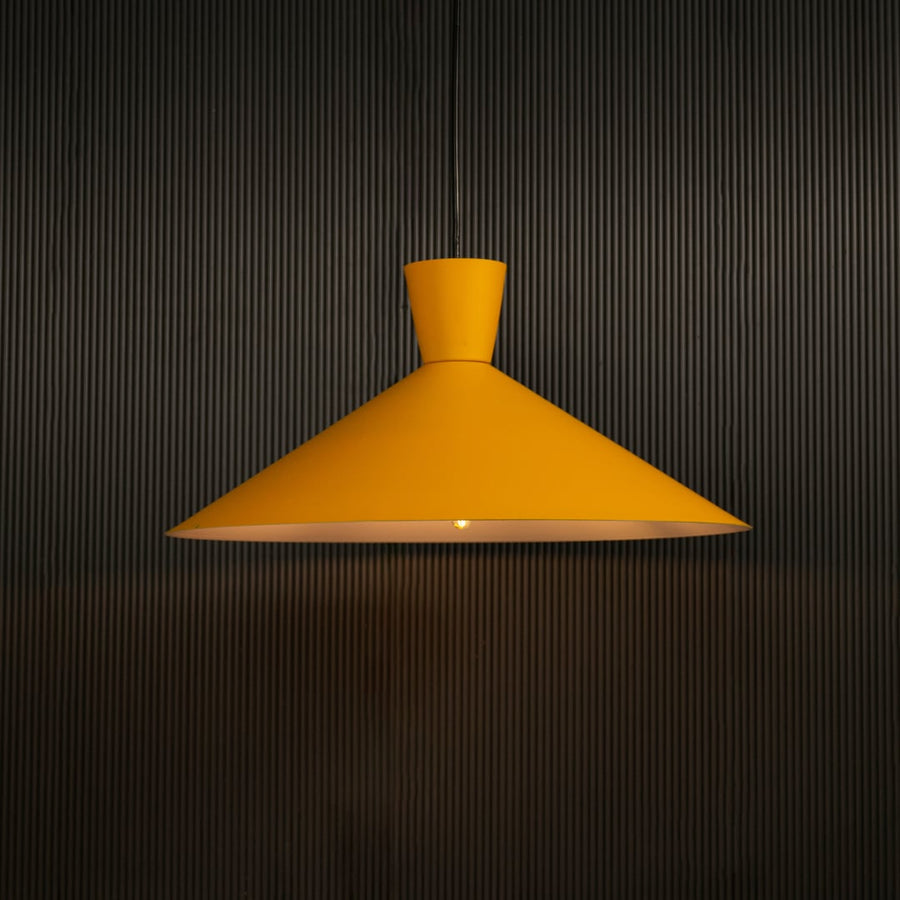 Yellow cone pendant light against dark panel wall with light on for bright modern décor.