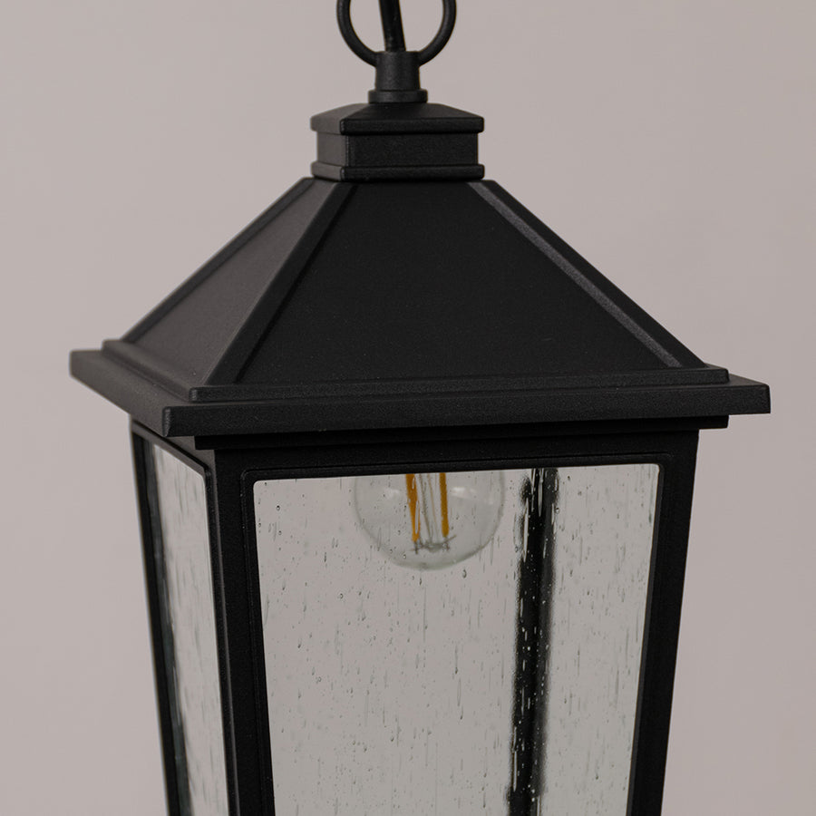 Closeup outdoor lantern in black metal finish with glass panels and top detail for entrance or garden decor lighting white background.