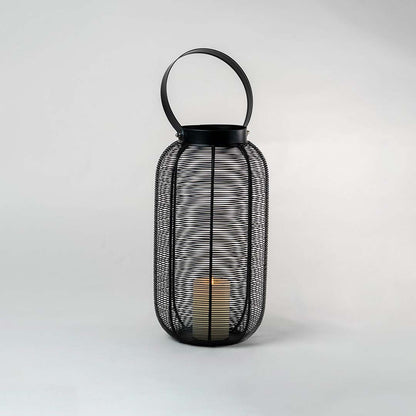 Illuminated black metal wire lantern isolated on white background showing warm candle glow casting shadows through mesh design.