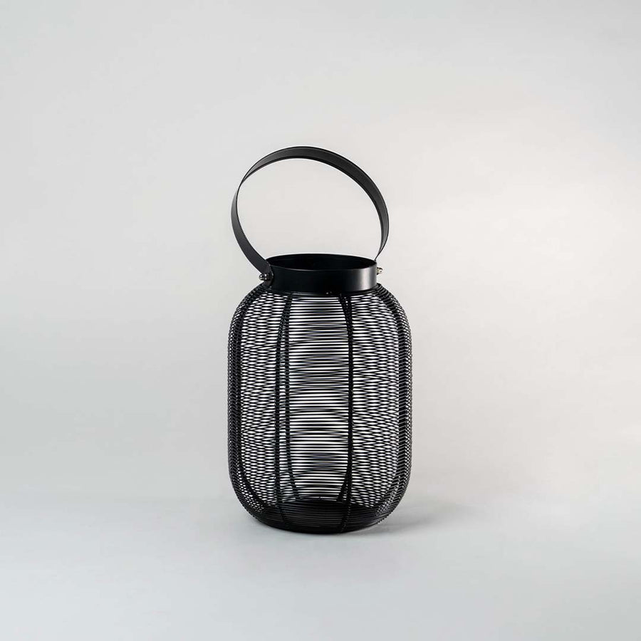 Unlit tall copper metal wire lantern standing on white background displaying sleek cylindrical shape and handle for contemporary styling.