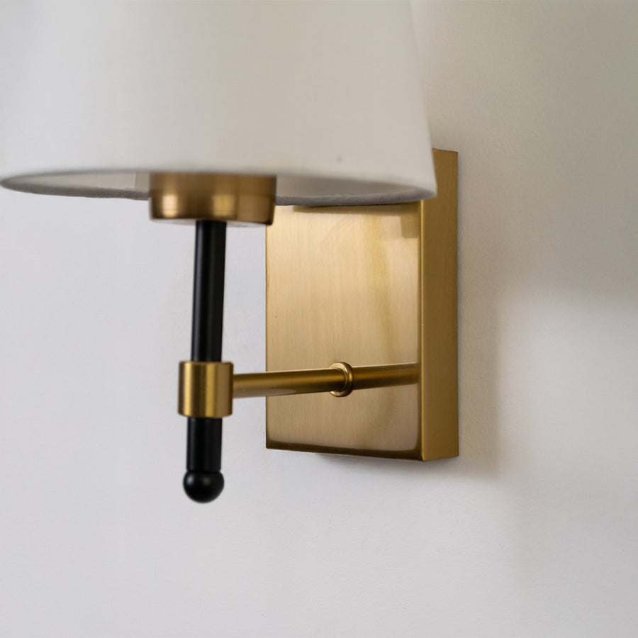 Closeup wall light in gold metal finish with fabric shade for bedroom or living room decor lighting white background.