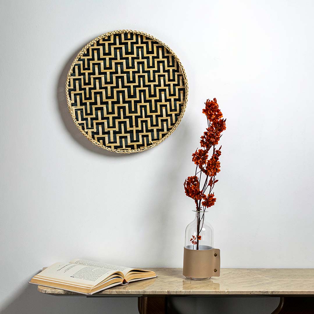 Black and natural woven bamboo basket with geometric zigzag pattern displayed as bohemian handcrafted wall decor art.