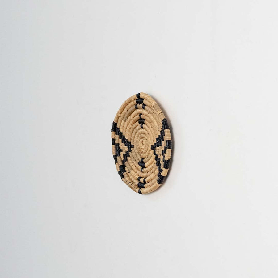 Round jute and black woven wall basket decor handmade rustic boho star design wall art accent piece shown from side view.