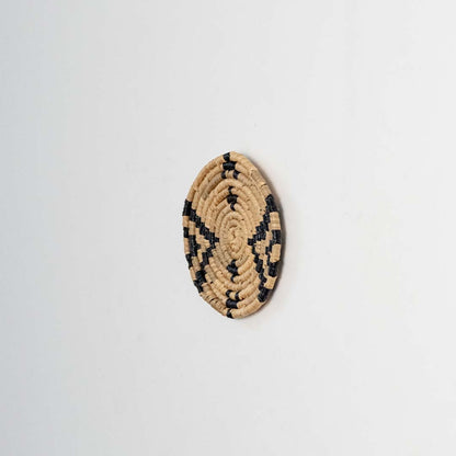 Round jute and black woven wall basket decor handmade rustic boho star design wall art accent piece shown from side angle.