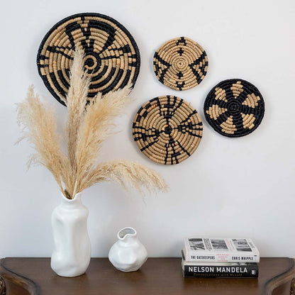 Set of handwoven jute wall basket decor in beige and black rustic boho star and spiral designs styled on white wall with vase