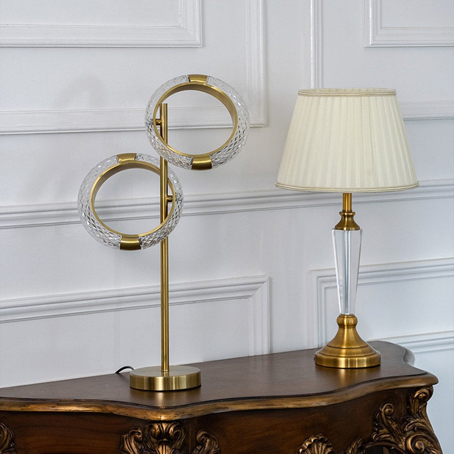 Grouped crystal ring table lamp styled with decorative accessories in elegant interior creating ambient lighting decor table lamp.
