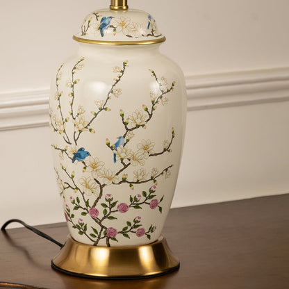 Close view of off white ceramic table lamp base with intricate floral pattern gold accents and elegant detailing.