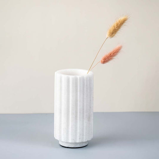 White marble vase with fluted design styled with dried stems ideal for modern living room table decor and floral arrangements.