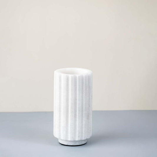 White ceramic decorative vase with vertical ribbed texture for shelf styling and contemporary home decor displays.