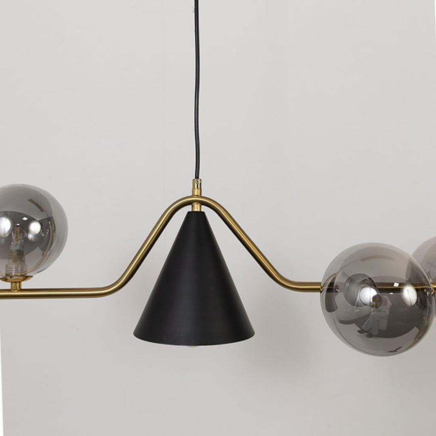 Closeup view of the chandelier showcasing its metallic globes curved golden bar and matte black cone detail with refined craftsmanship.