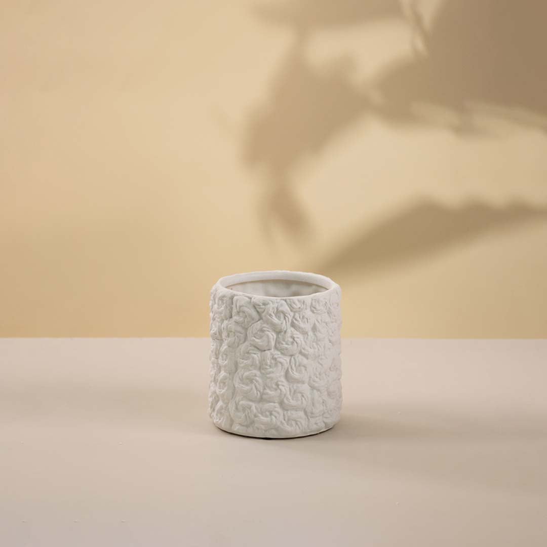 Elegant white textured ceramic vase with artistic surface detailing highlighted against white background.