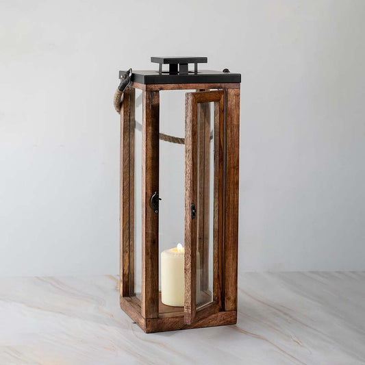 Rustic tall wood and glass lantern with candle lit shown on white background for modern home accents.