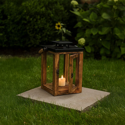Rustic wooden lantern with candle lit placed on garden stone creating cozy outdoor evening ambiance.