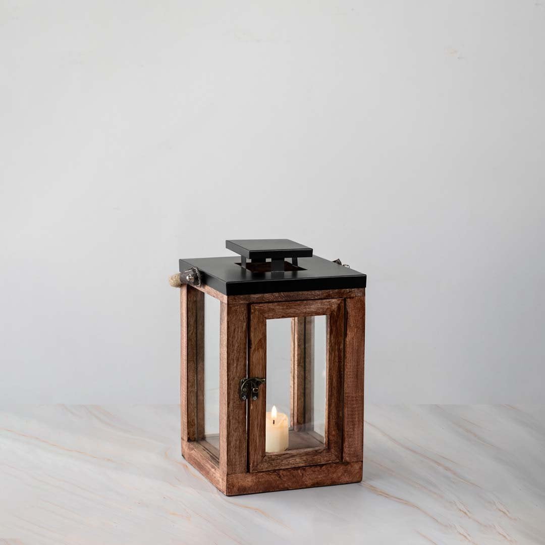 Wooden lantern with candle lit shown on white background for patio lighting decor.