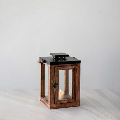 Wooden lantern with candle lit shown on white background for patio lighting decor.