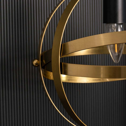 Detailed view of a spherical pendant light showing layered metal bands and central bulb holder capturing warm metallic tones and detailed craftsmanship.