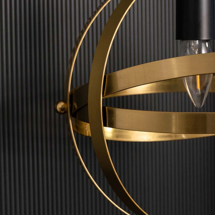 Detailed view of a spherical pendant light showing layered metal bands and central bulb holder capturing warm metallic tones and detailed craftsmanship.