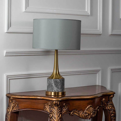 Grey shade gold neck table lamp on carved console table with light off and white panel wall background for luxury contemporary décor.