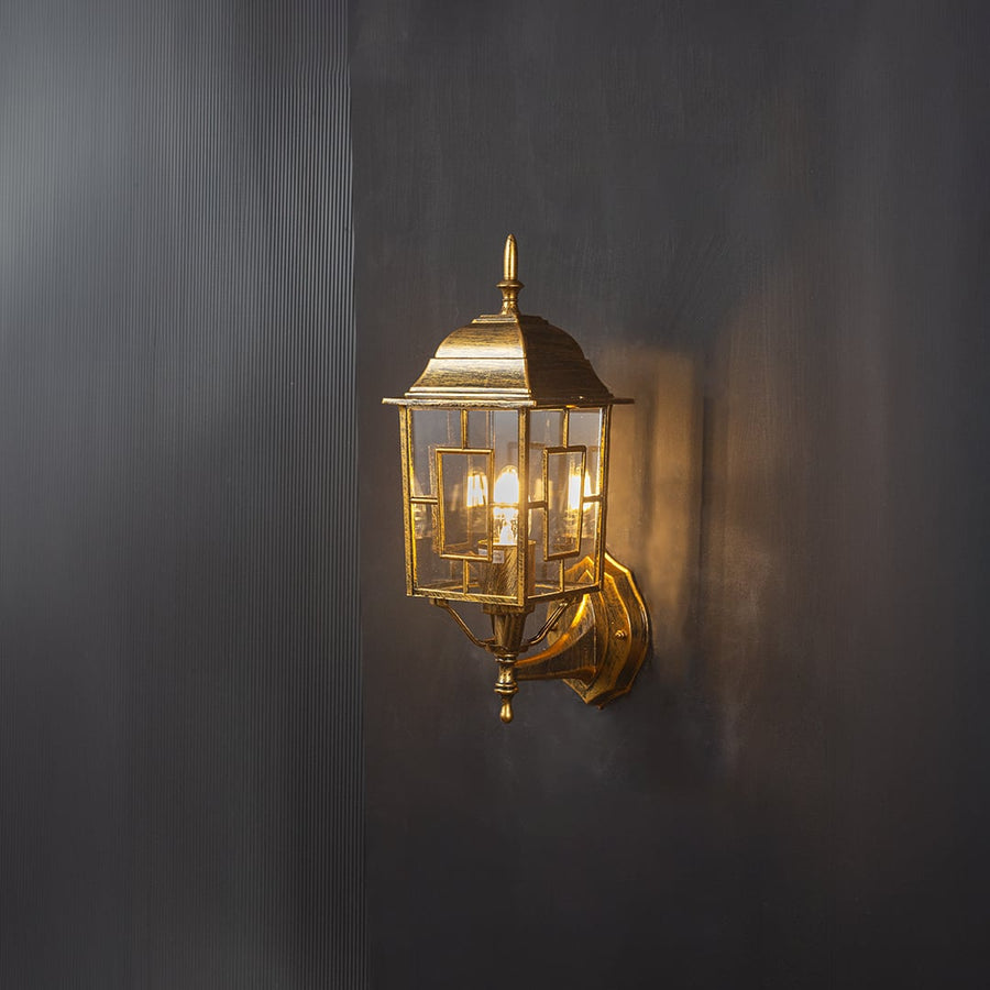 Lantern wall light glowing on a black background highlights warm illumination and intricate frame.