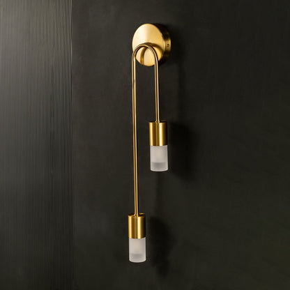 A modern dual gold metal wall lamp with frosted glass shades shown with lights off against a dark background emphasizing its sleek minimal silhouette.
