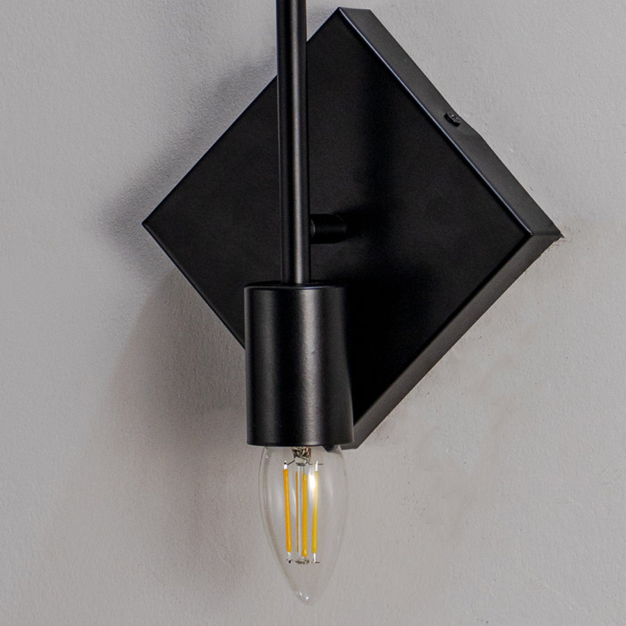 Minimal wall light with black diamond plate and exposed filament bulb on neutral background industrial style lighting for home decor.